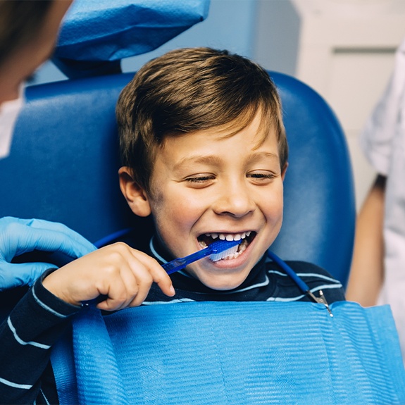 Child in dental chair brushing teeth