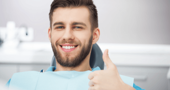 Smiling man giving thumbs up after dental checkup