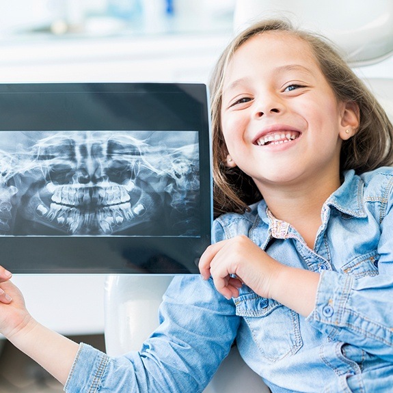 Child holding up her x-rays during dental checkup