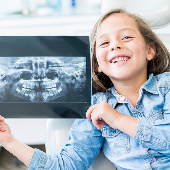 Child holding up her x-rays during dental checkup