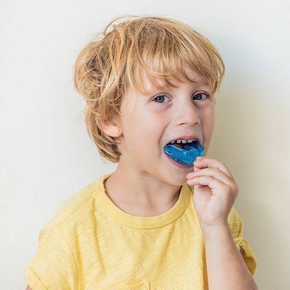 Young boy placing a blue mouthguard
