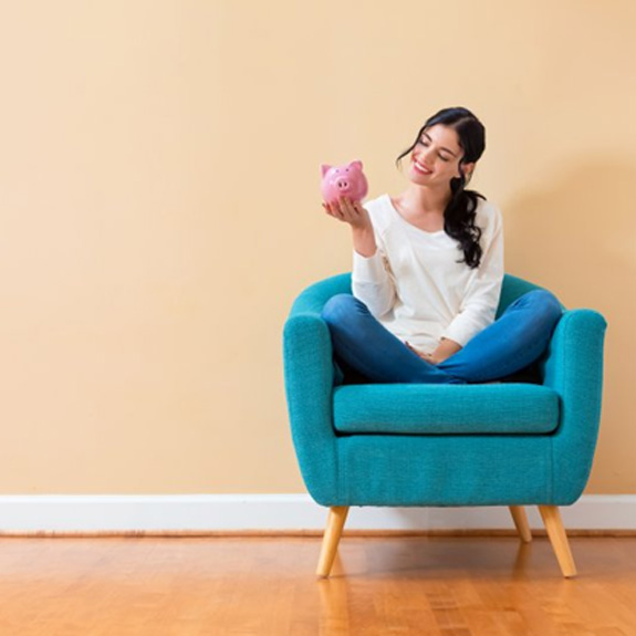 Woman sitting in a comfy chair and holding a piggy bank