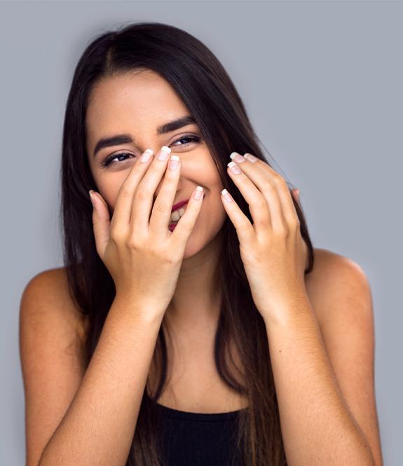 Woman in need of cosmetic dentistry covering her smile