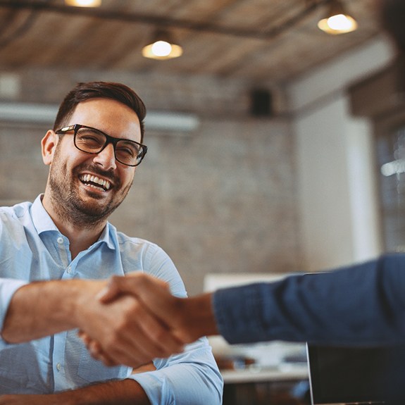 a person smiling and shaking someone’s hand