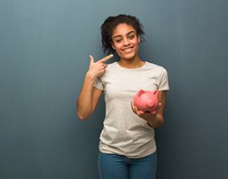 woman holding a piggy bank and pointing to her smile 