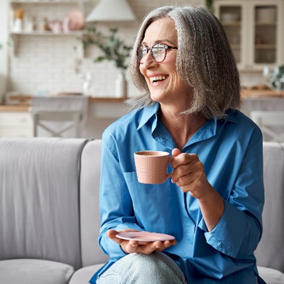 Woman smiling while enjoying cup of tea at home