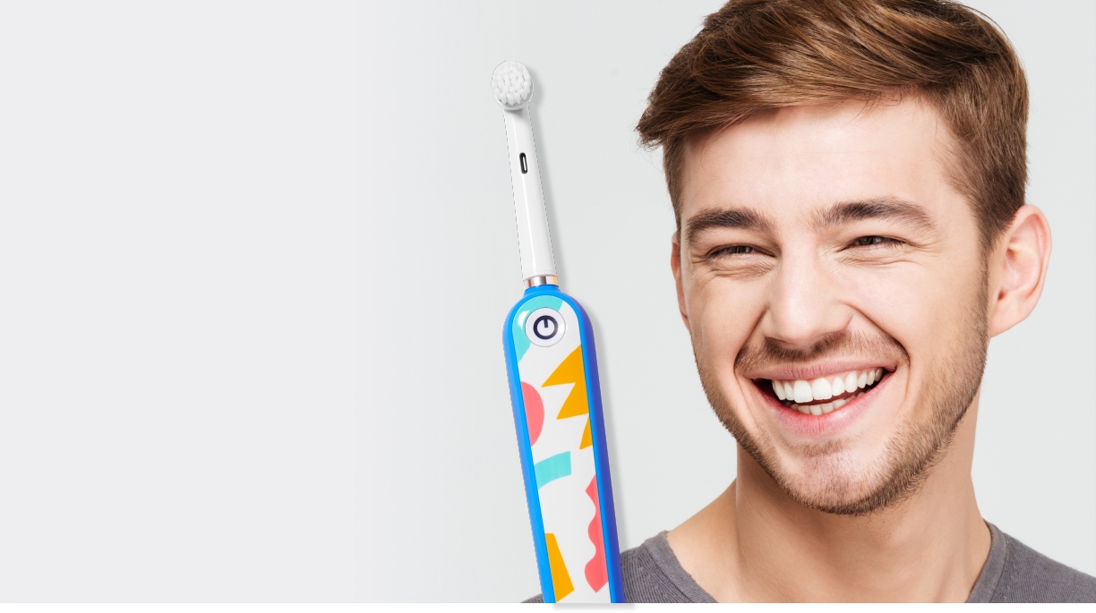 Smiling young man holding an electric toothbrush