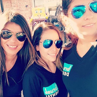 Smiling dental team members wearing sunglasses outdoors