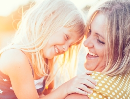 Mother holding her laughing daughter outdoors