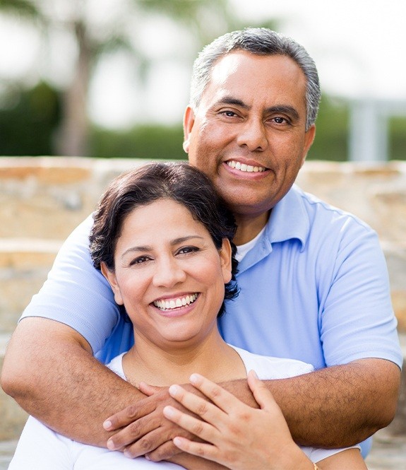 Older man and woman sharing healthy smiles after replacing missing teeth