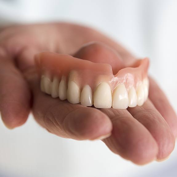 Hand holding a full denture