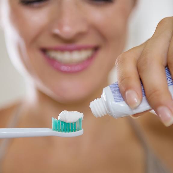 Woman placing toothpaste on toothbrush