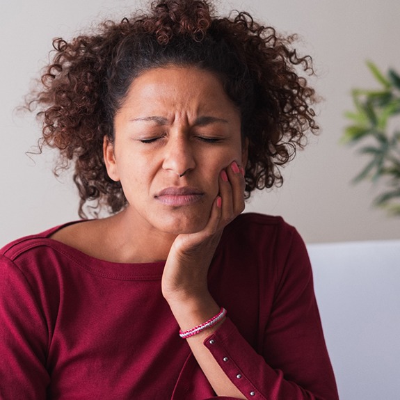 Woman with toothache sitting on couch at home