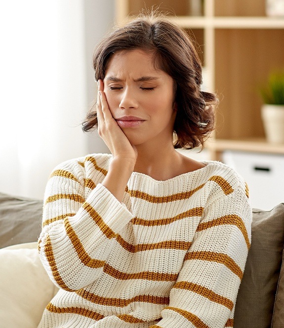 Woman in need of wisdom tooth extraction holding jaw