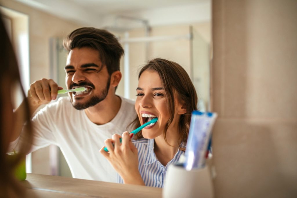 Man and woman brushing their teeth with tips from a family dentist