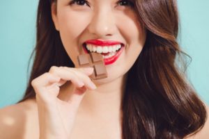 young woman biting into a piece of chocolate 