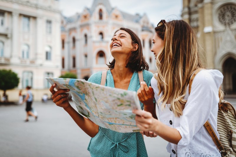 Women holding a map and smiling while visiting a foreign city