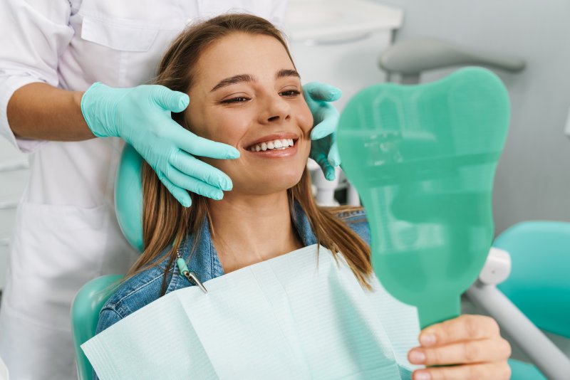 Young woman looking in mirror at dentist's office