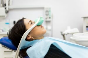 Profile view of woman in dental chair wearing green nitrous oxide mask